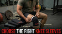 A man sitting on a gym bench in a weight room, using a tape measure around the lower part of his thigh just above his knee