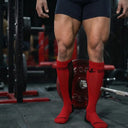 Athlete wearing red deadlift socks India for shin protection during powerlifting training with a loaded barbell in the gym.